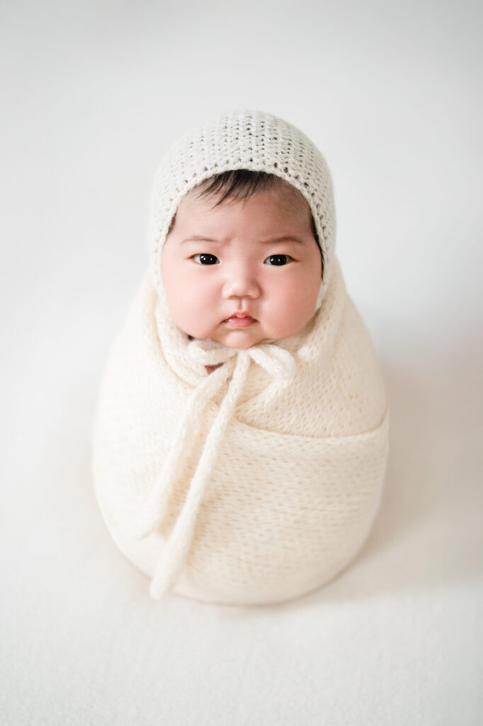 白いニットのおくるみに包まれた赤ちゃんのニューボーンフォト